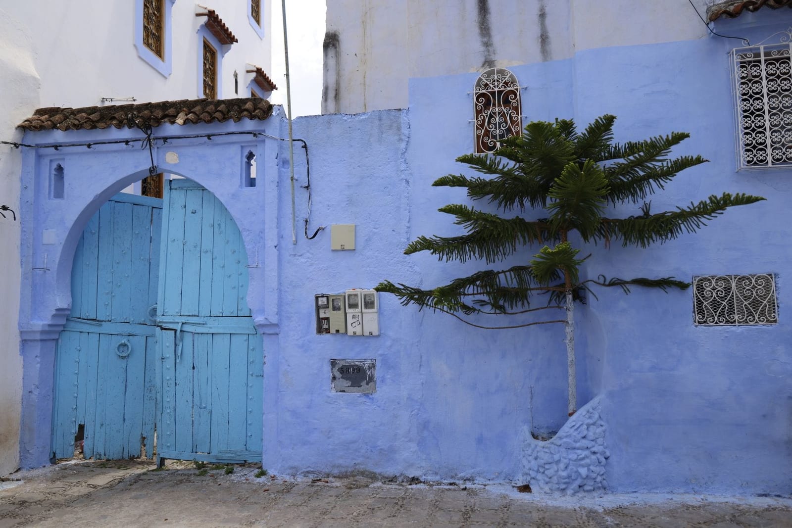 A blue-painted arch and carved wooden door in a Moroccan town