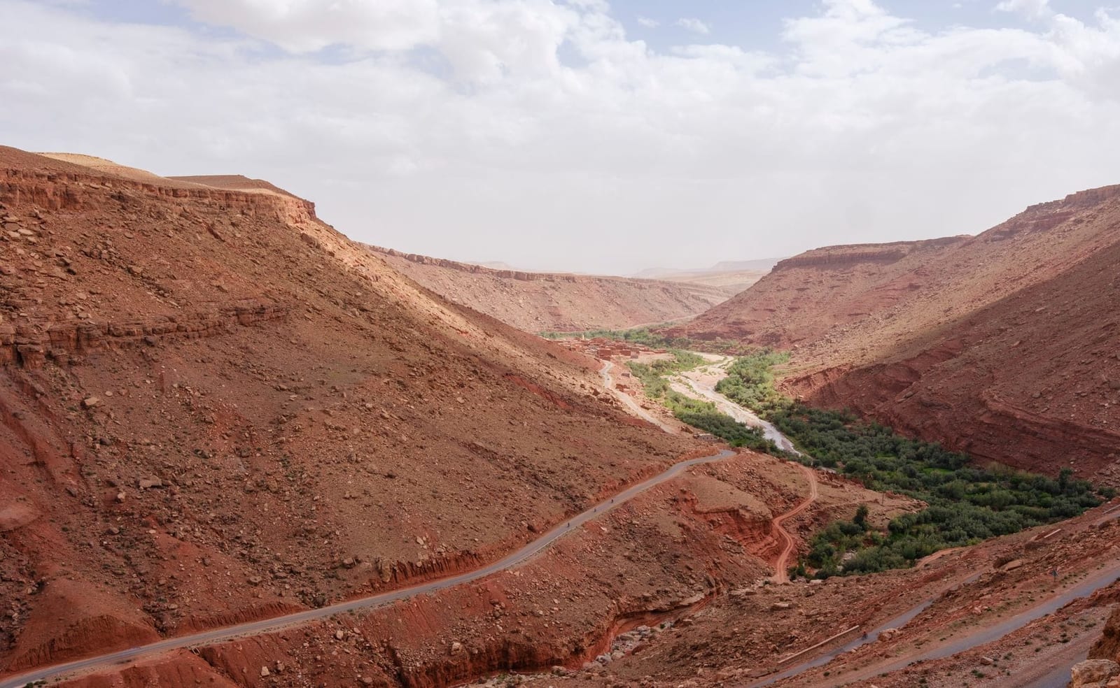 Red canyon walls and green vegetation in a Moroccan gorge
